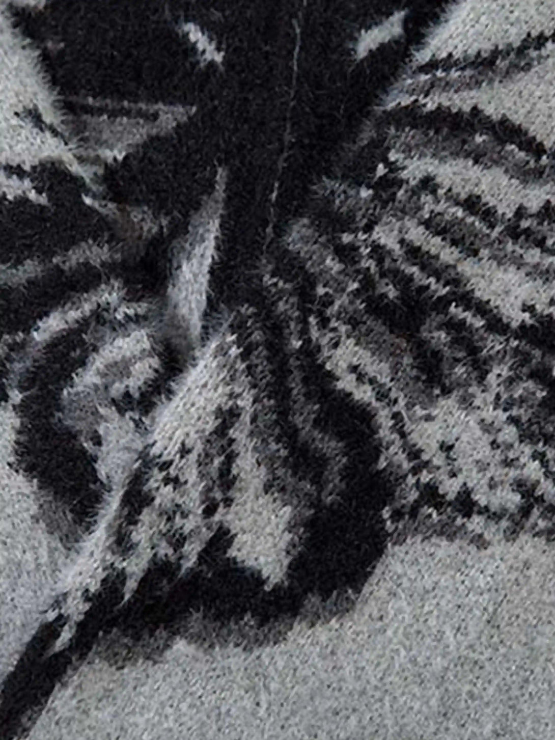 A tight crop highlighting TALISHKO's mohair cardigan with a striking black butterfly pattern.