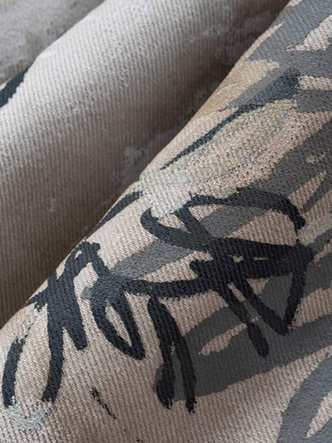 Zoomed-in texture of TALISHKO hand-painted graffiti on baggy jeans, emphasizing artistic design.