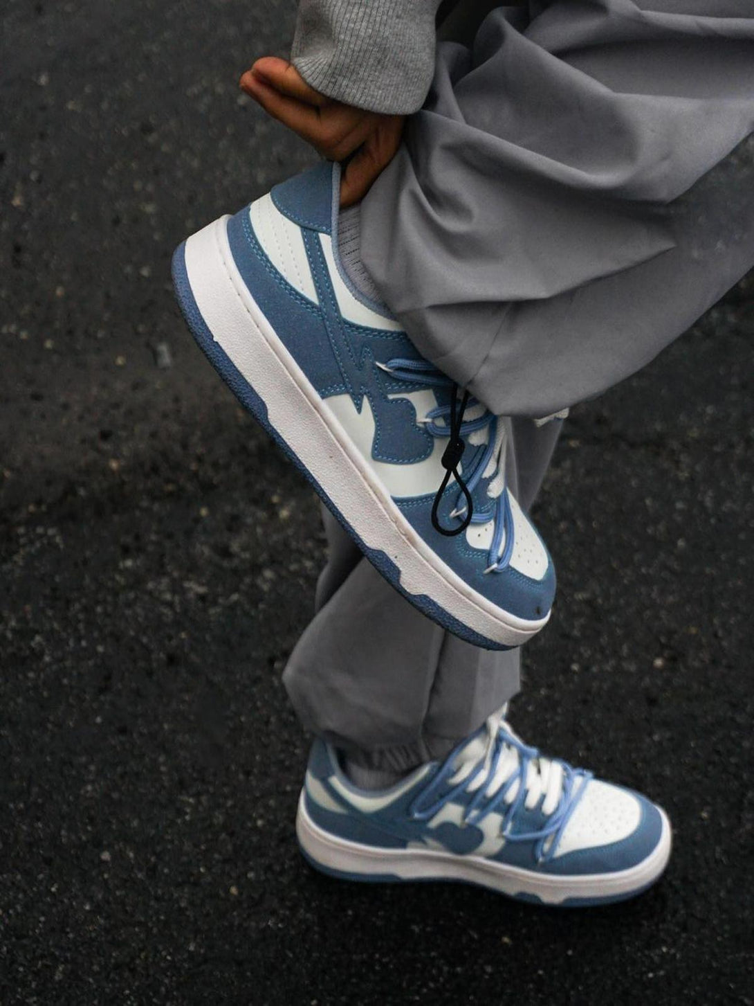 TALISHKO haze blue board shoes worn with gray pants, showcasing sleek design and stylish laces.