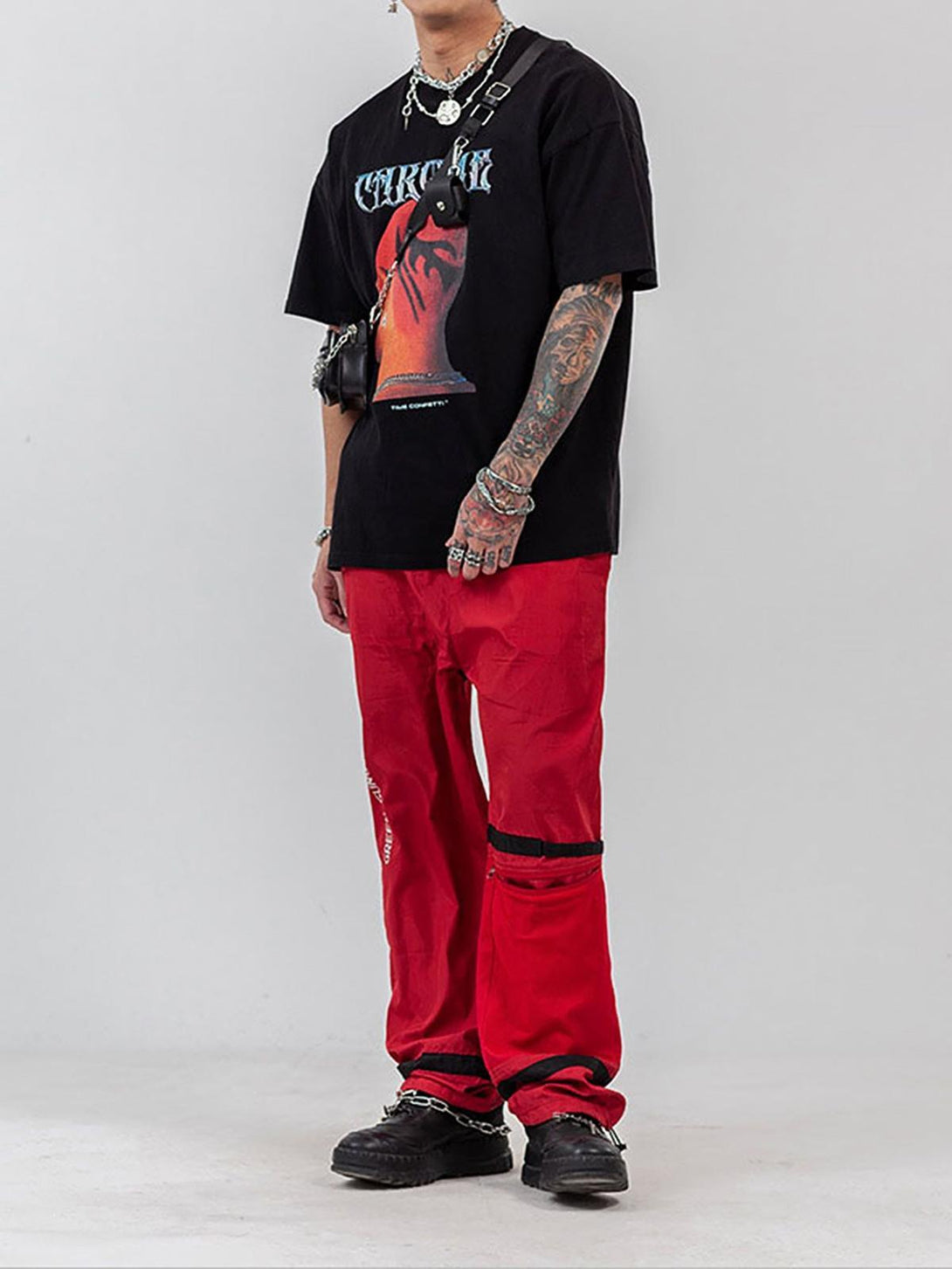 Model in TALISHKO hip hop T-shirt with bold head print, paired with red pants and accessories.