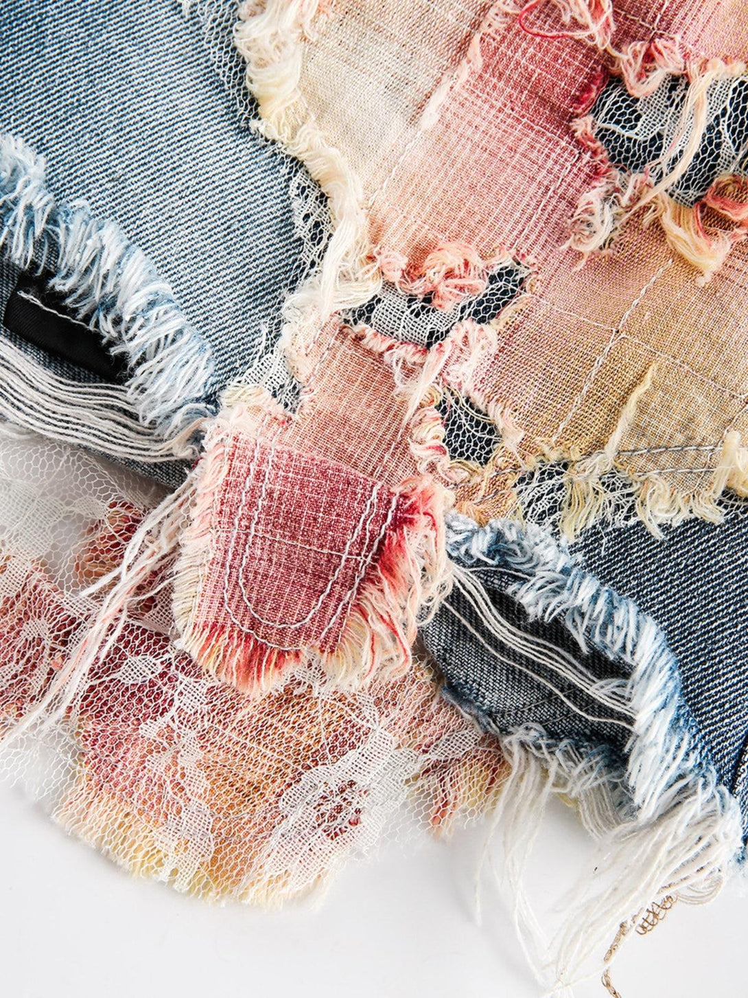 A detailed view of TALISHKO denim jorts, showcasing colorful lace and distressed textures.