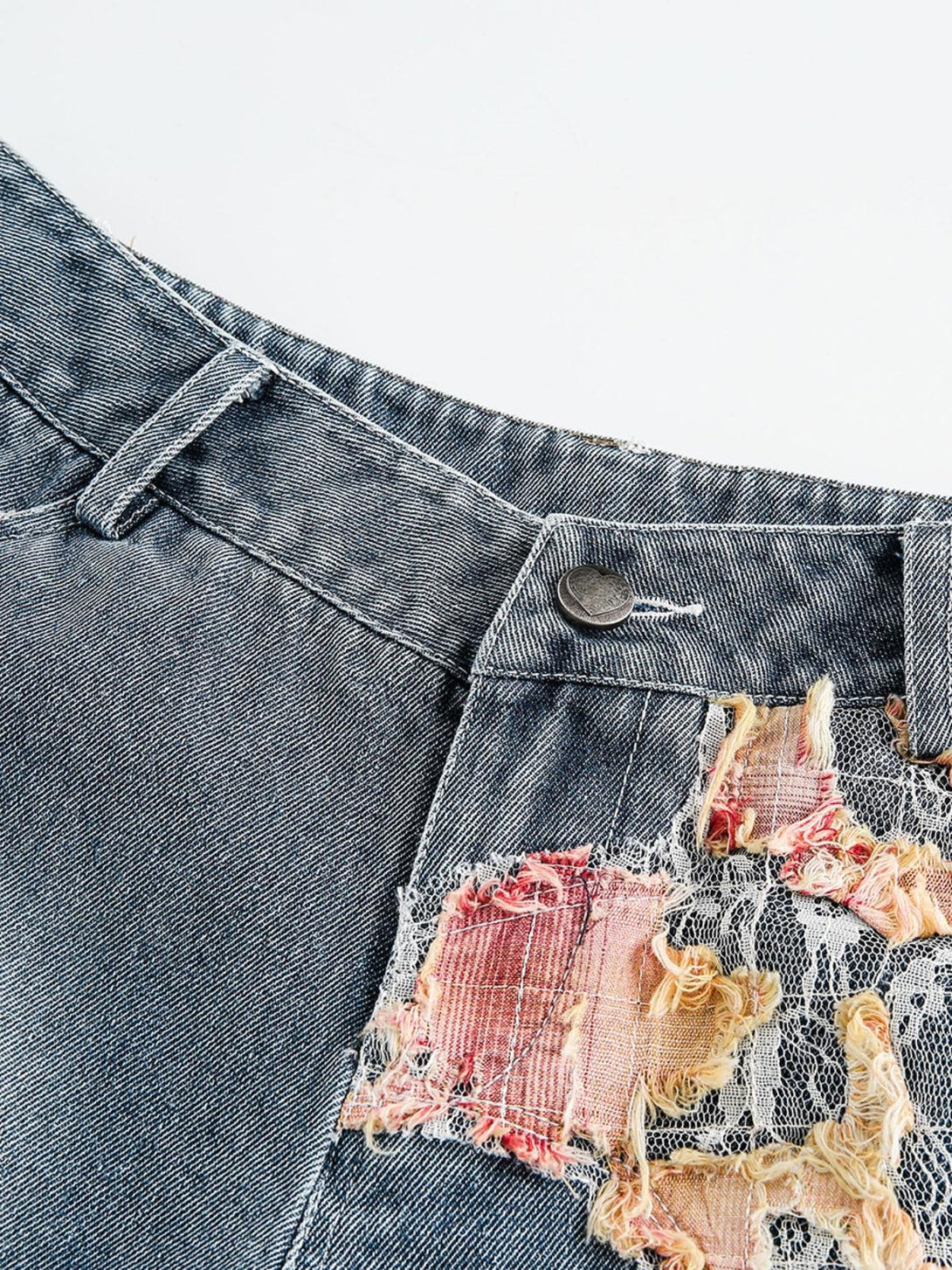 Intricate look at TALISHKO denim shorts with detailed lace patches and distressed texture.