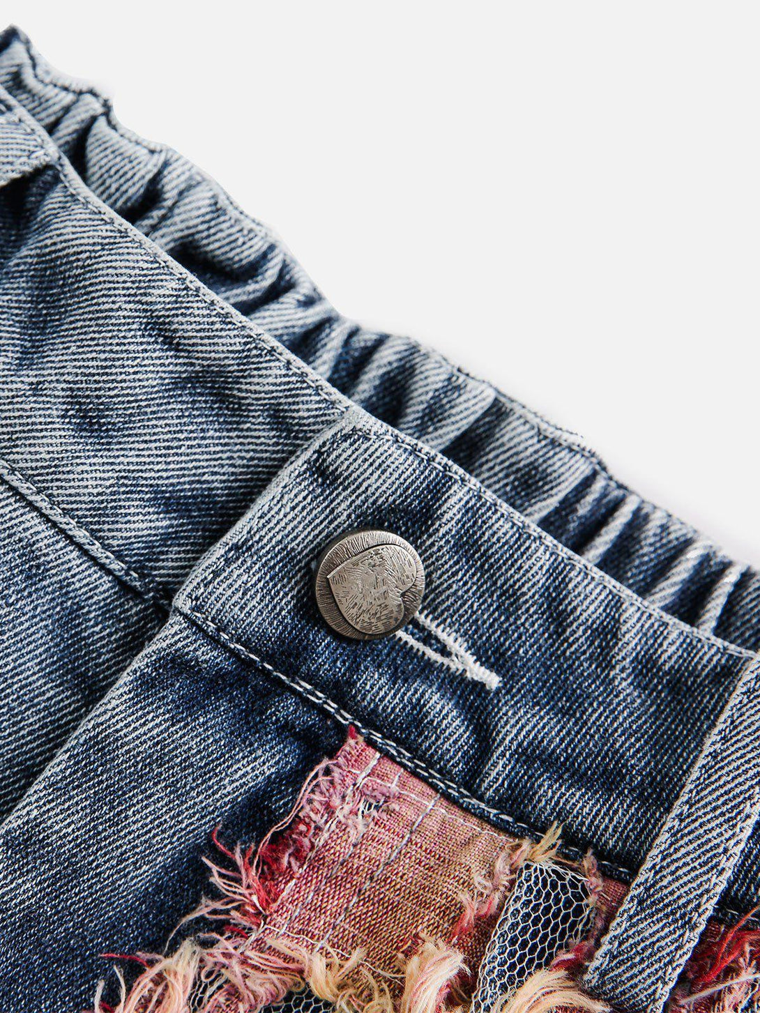 A close-up of TALISHKO denim jorts showcasing detailed craftsmanship with lace patchwork.