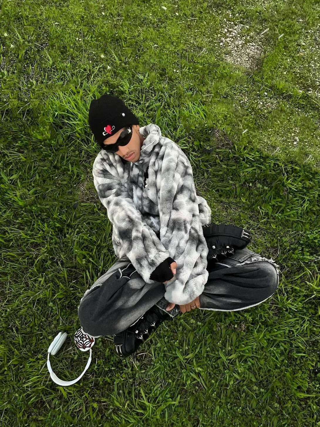 TALISHKO's tie-dye urban jacket in faux lambswool, styled casually while lounging on grass.
