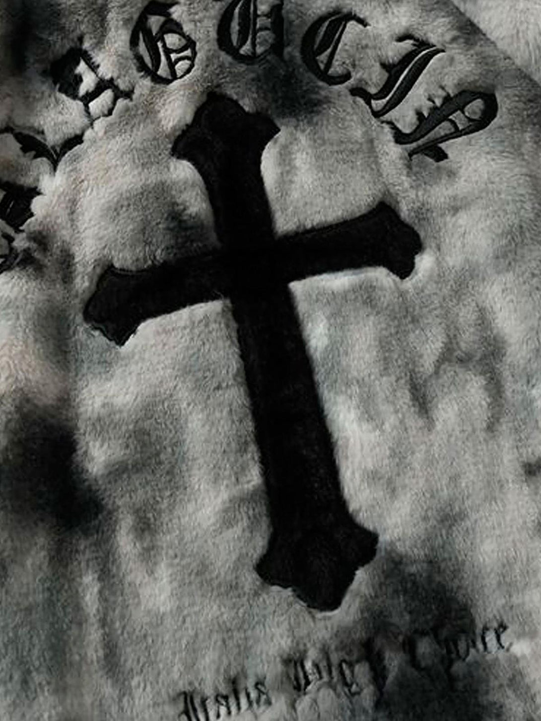 A tight crop highlighting the cross detail on TALISHKO's tie-dye faux lambswool jacket.