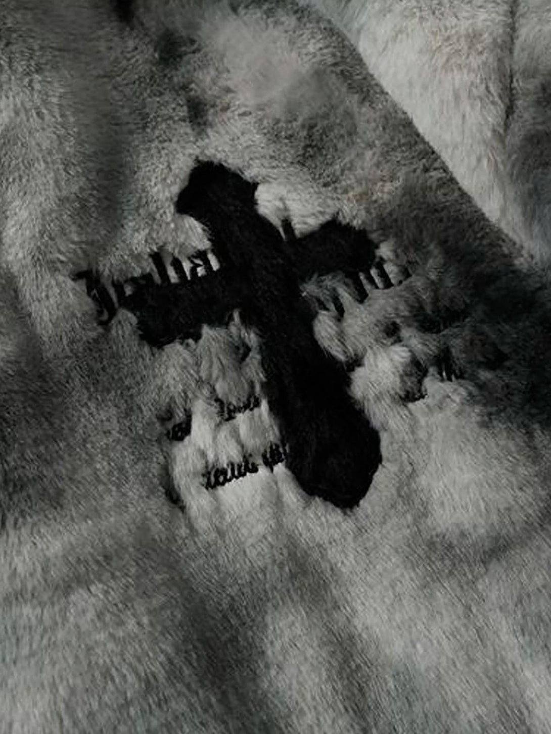 Intricate look at TALISHKO's tie-dye jacket, featuring plush faux lambswool and cross detail.