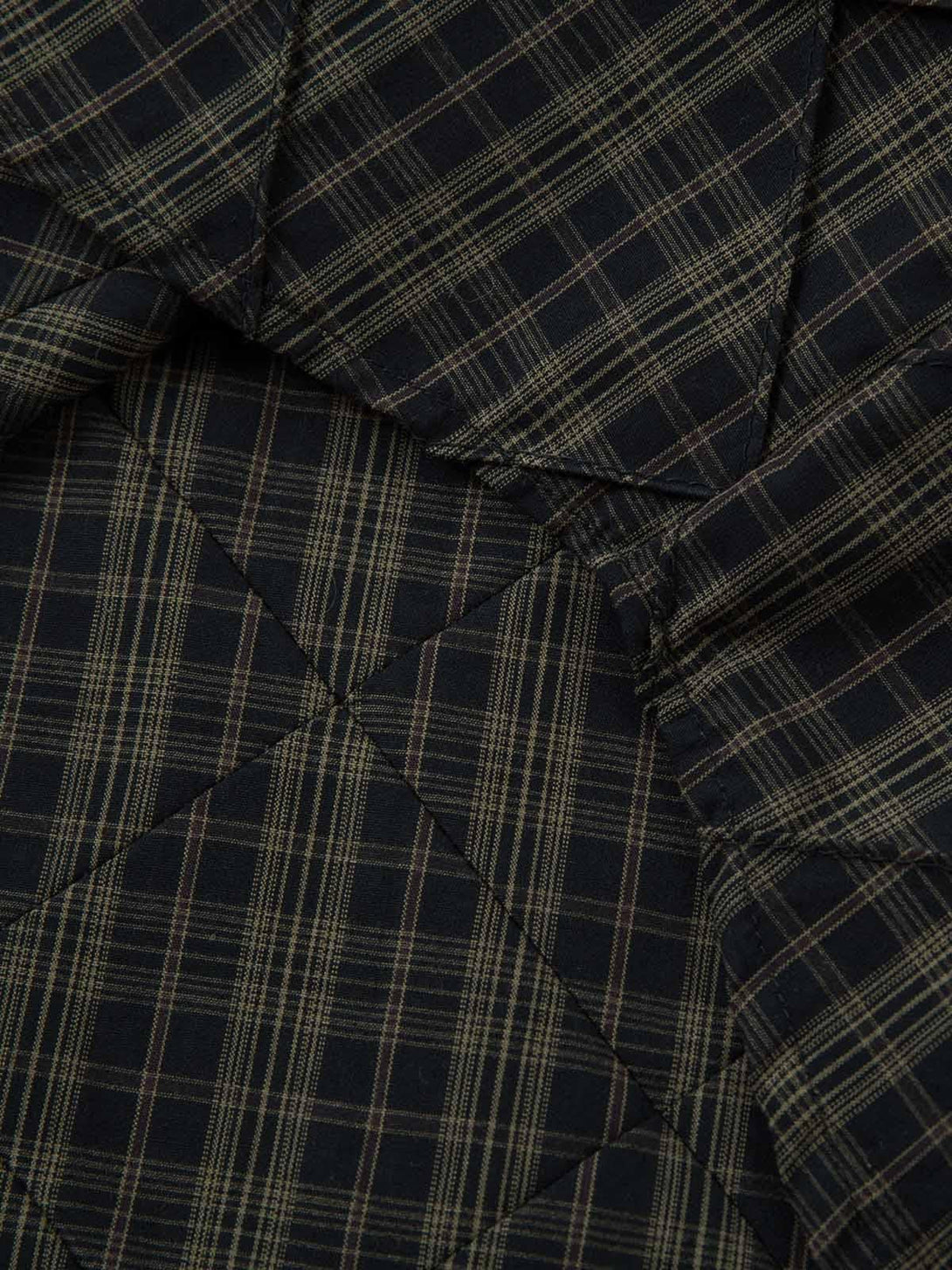 A close-up of the plaid pattern and stitching on the TALISHKO pleated polo shirt.