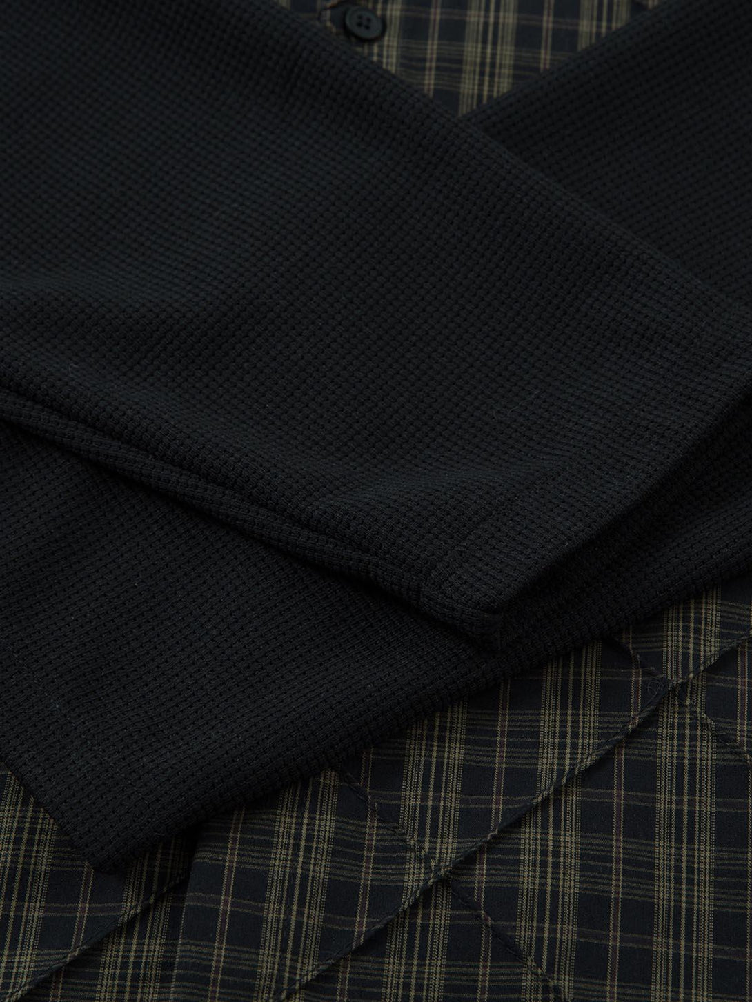 Detailed fabric and stitching of the TALISHKO plaid pleated faux two-piece polo shirt.