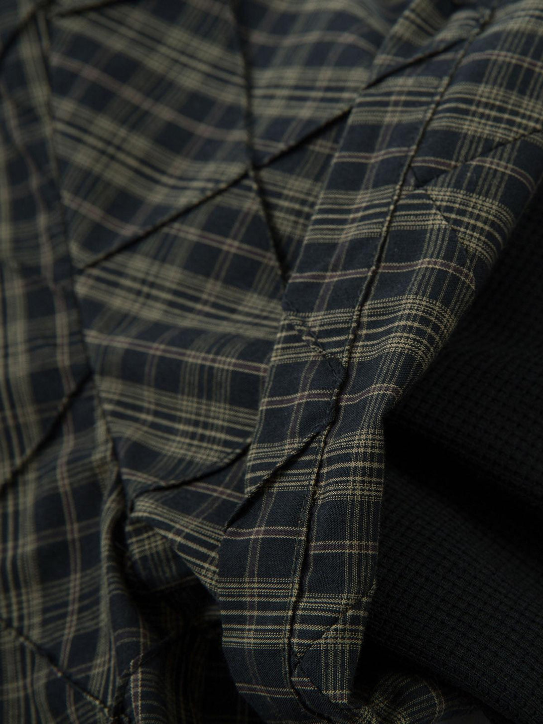 Texture and pattern showcased in the plaid pleated fabric of the TALISHKO polo shirt.