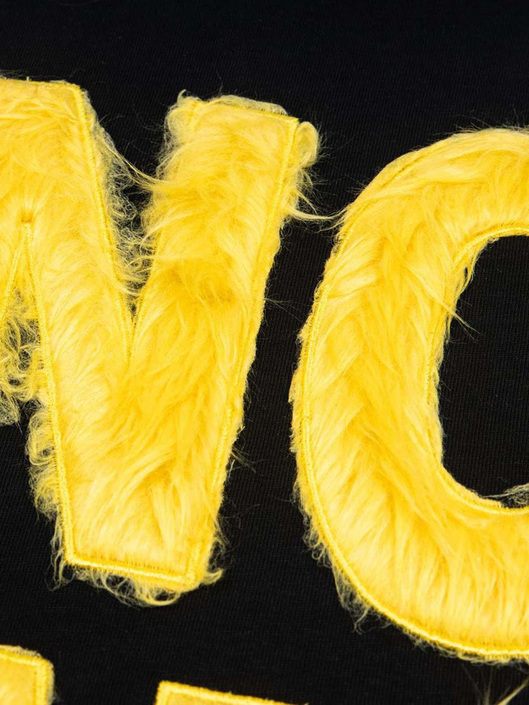 Fuzzy yellow texture on black TALISHKO T-shirt, emphasizing retro-inspired embroidery details.