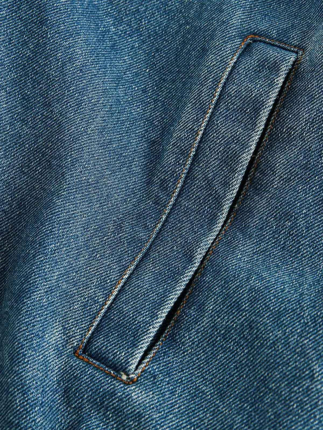 A detailed view of TALISHKO's denim jacket pocket, highlighting its sturdy stitching and texture.