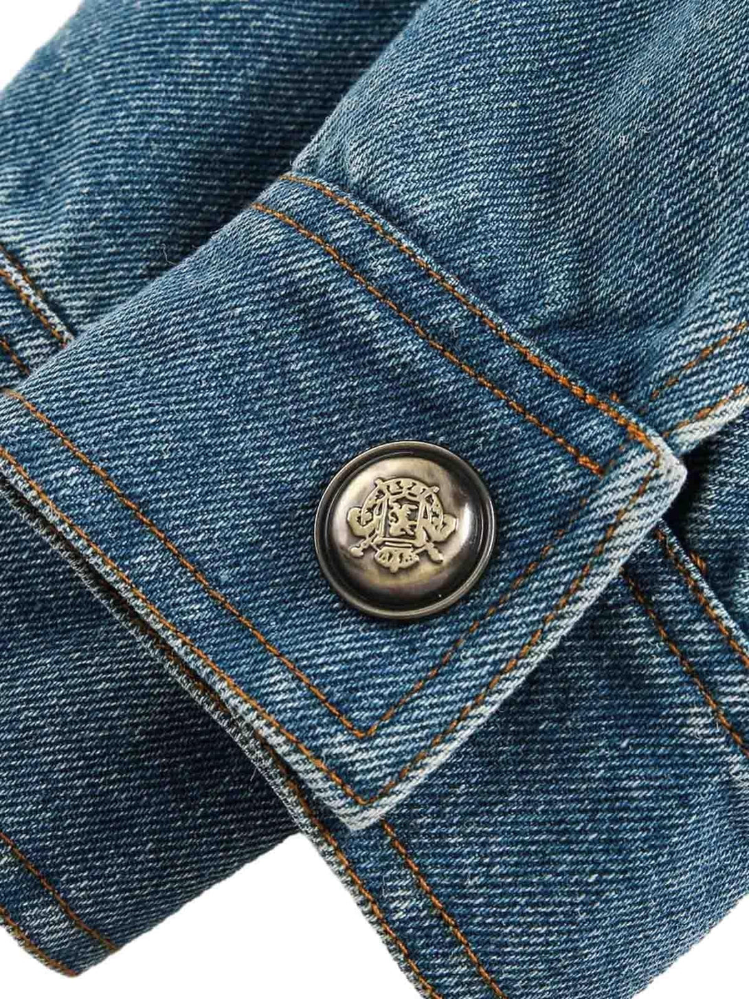 Intricate look at TALISHKO's denim jacket button, highlighting detailed stitching and texture.