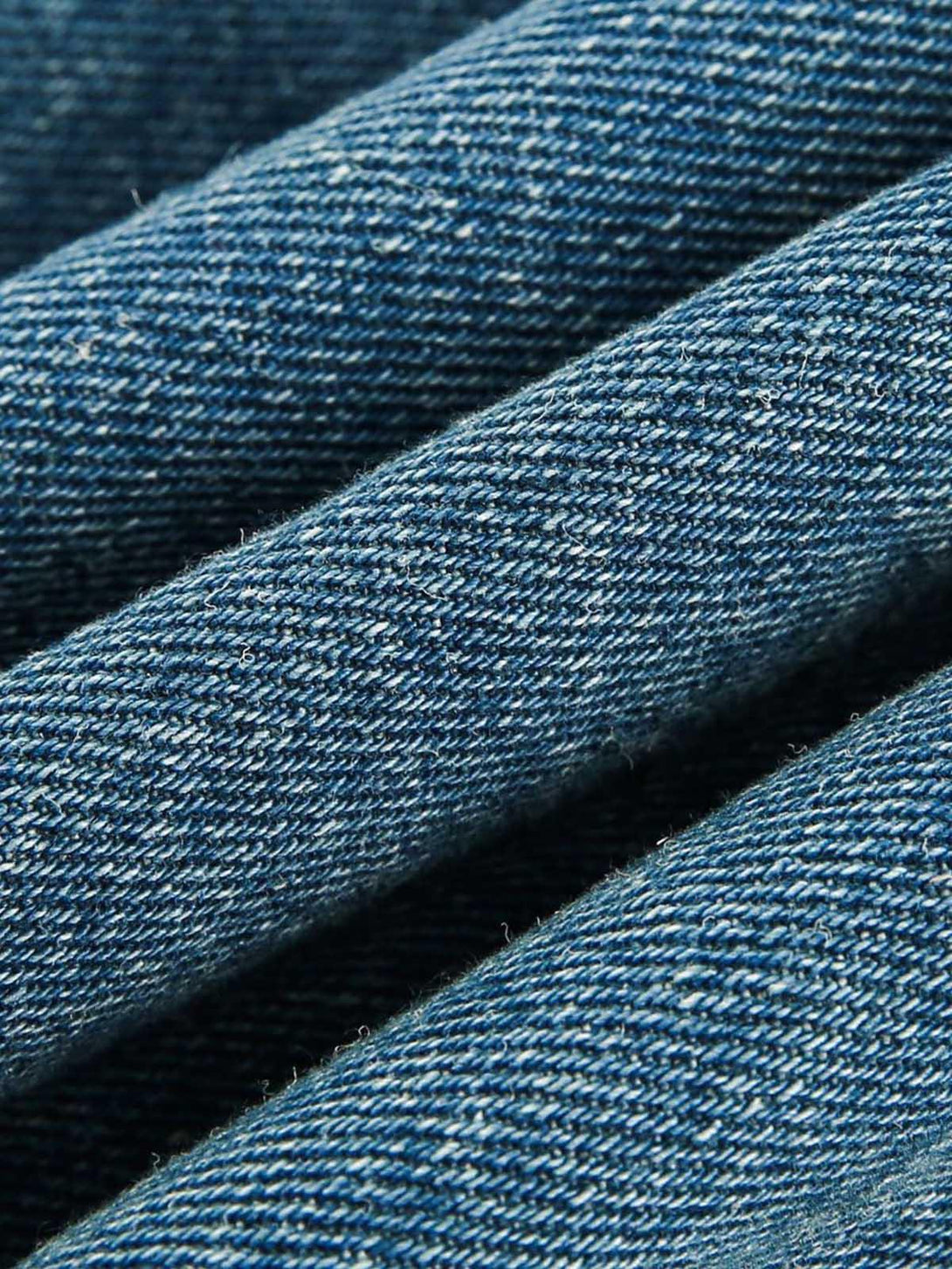 A tight crop highlighting the heavy washed denim texture on TALISHKO's work jacket.