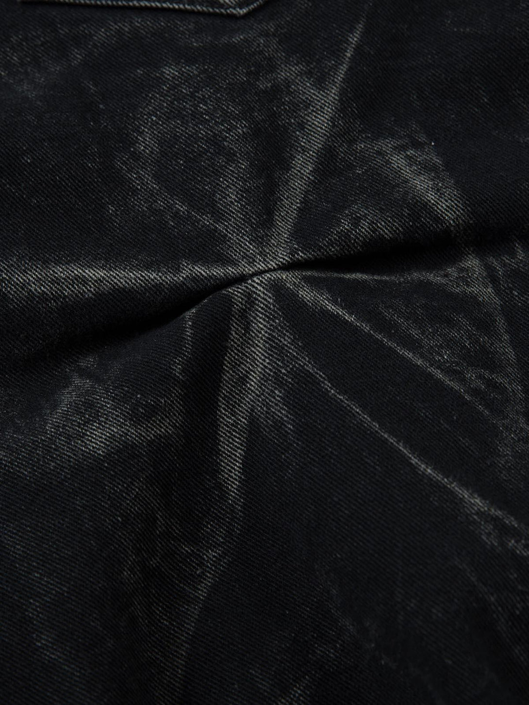 Zoomed-in texture of TALISHKO jeans highlighting the heavy washed, distressed fabric.
