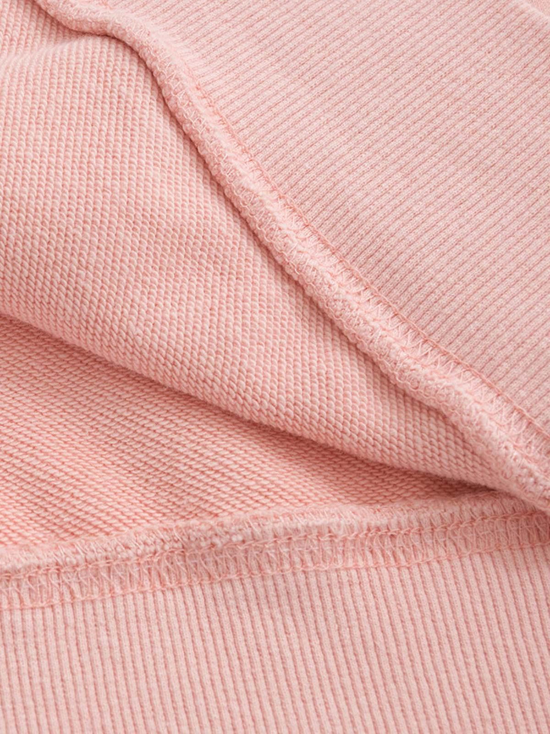 Intricate look at TALISHKO hoodie fabric, showcasing soft pink texture and detailed stitching.