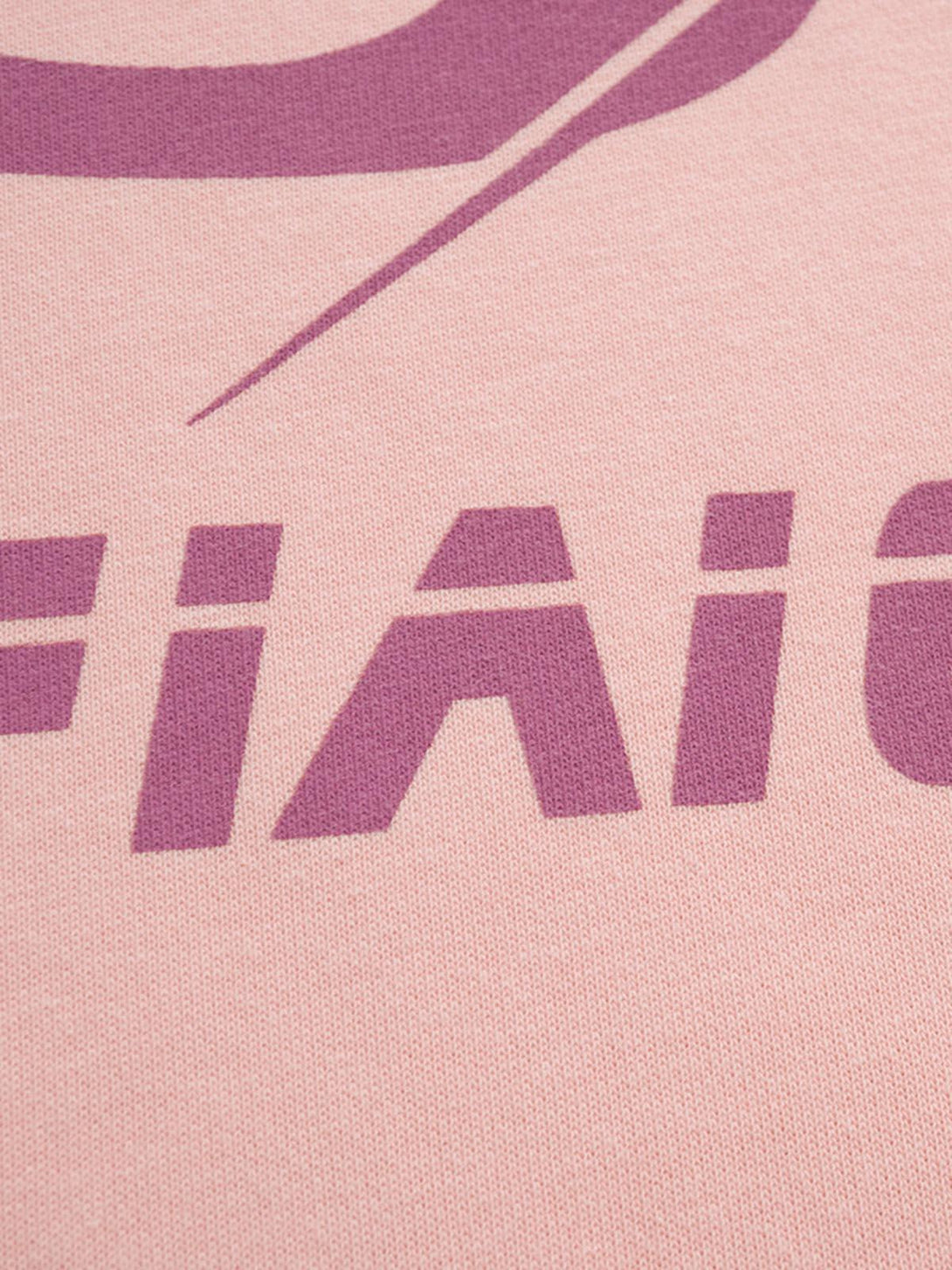 Zoomed-in texture of TALISHKO hoodie, showcasing bold purple lettering on a soft pink fabric.