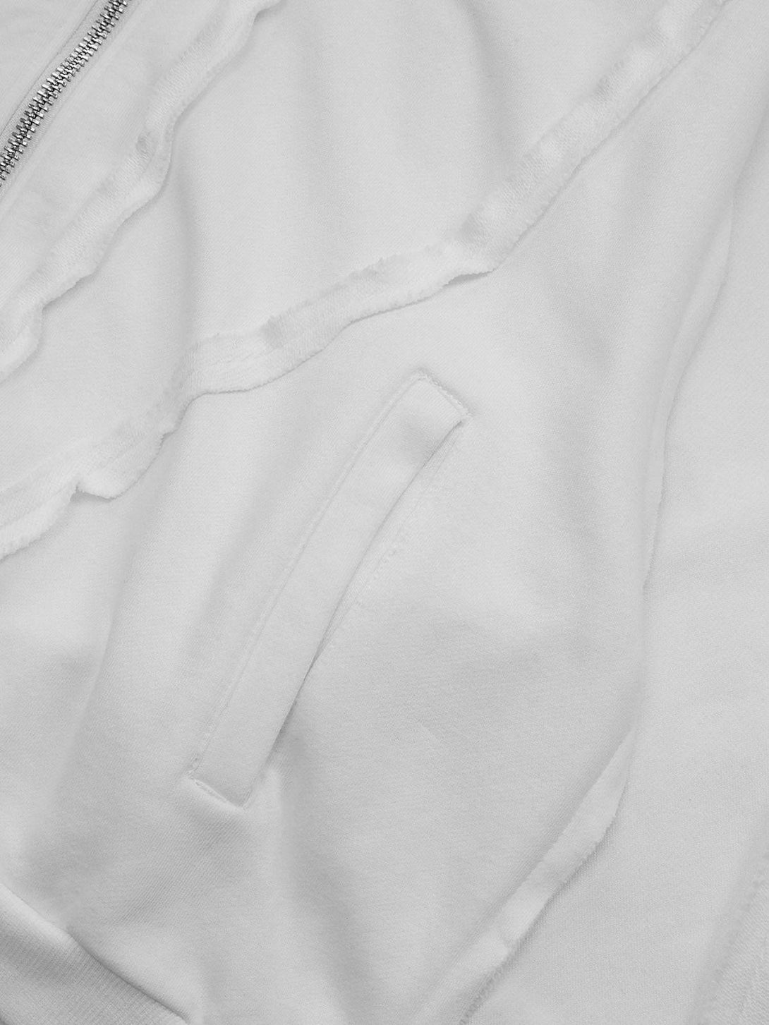 Focusing on the textured fabric and stitching of a white distressed hoodie by TALISHKO.