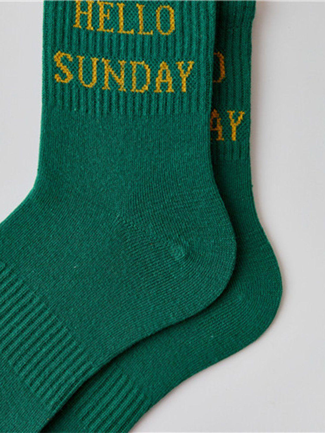 Green "HELLO SUNDAY" socks by TALISHKO with yellow lettering, perfect for relaxed weekends.