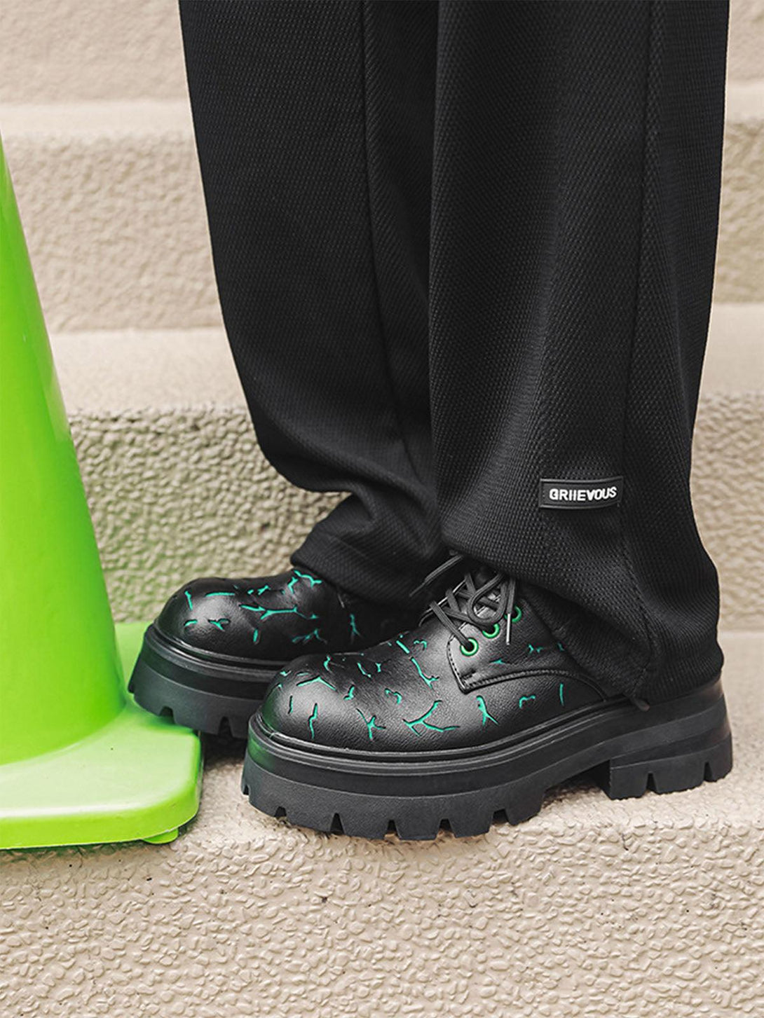TALISHKO crackle leather shoes with green accents and chunky soles, paired with black pants.