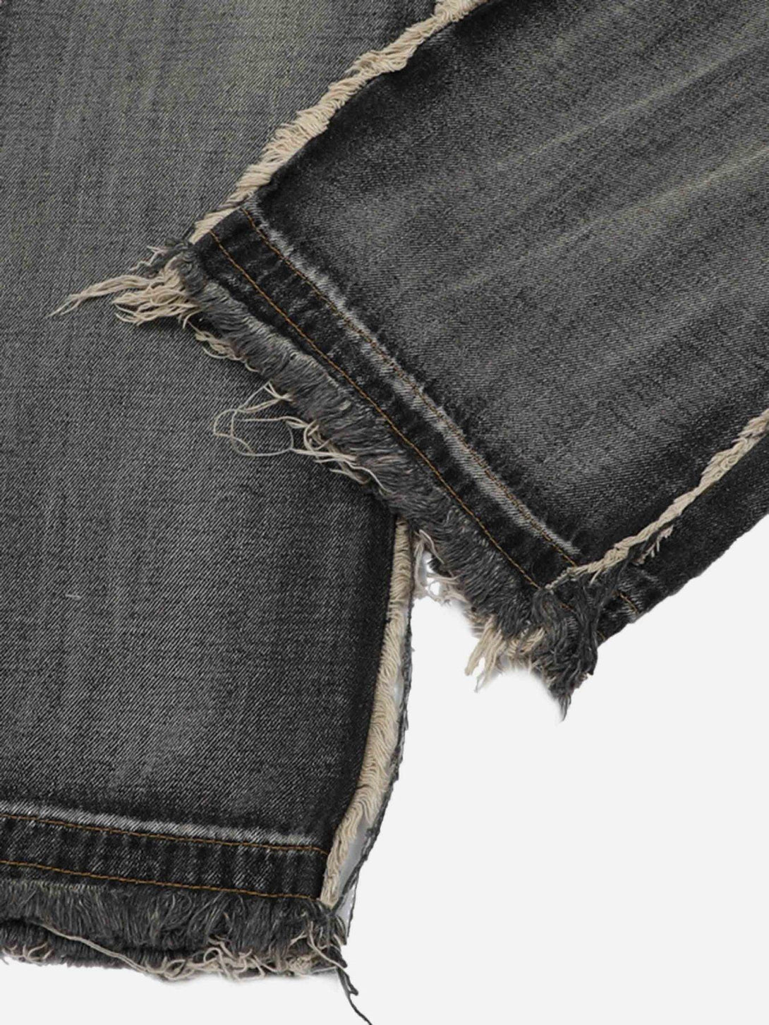 Detailed fabric and stitching of distressed raw edge jeans by TALISHKO, highlighting texture.