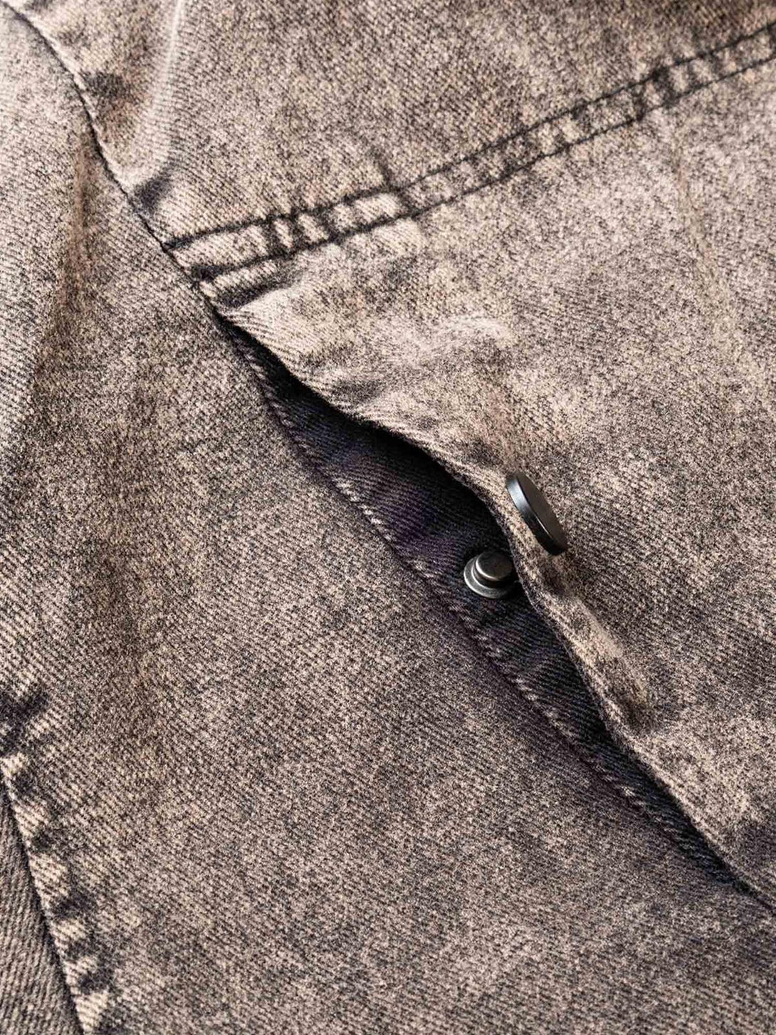 Zoomed-in texture of TALISHKO's distressed work jacket, showcasing intricate stitching and washed fabric.