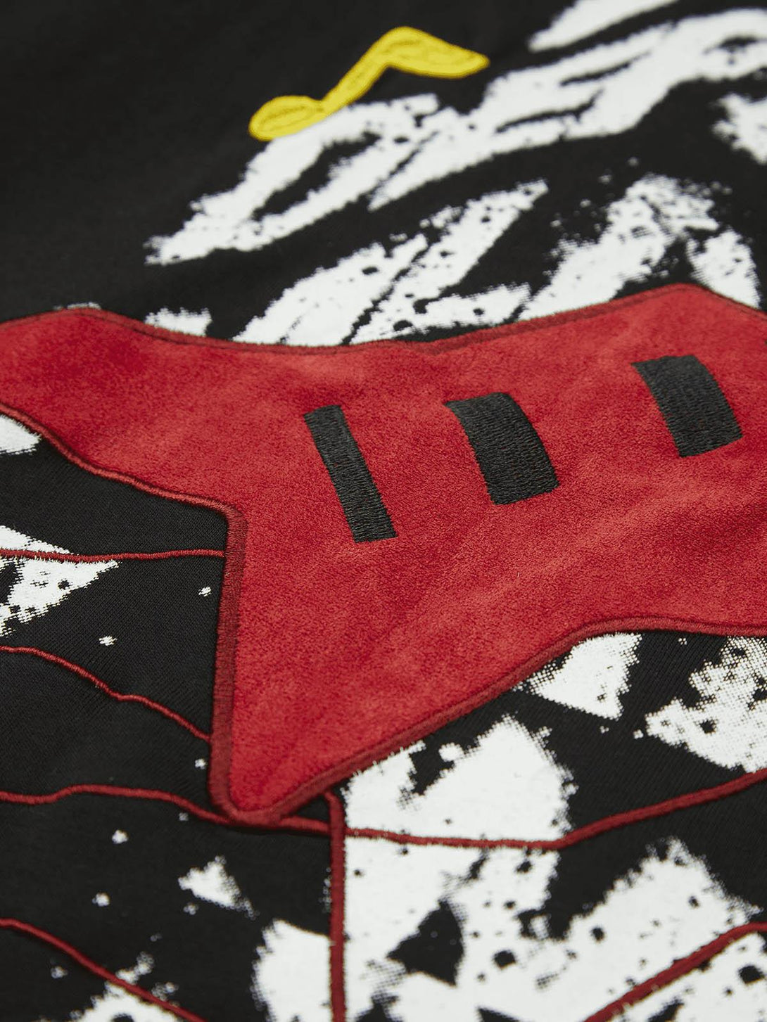 Intricate look at TALISHKO's T-shirt, highlighting unique red embroidery and bold graphic details.