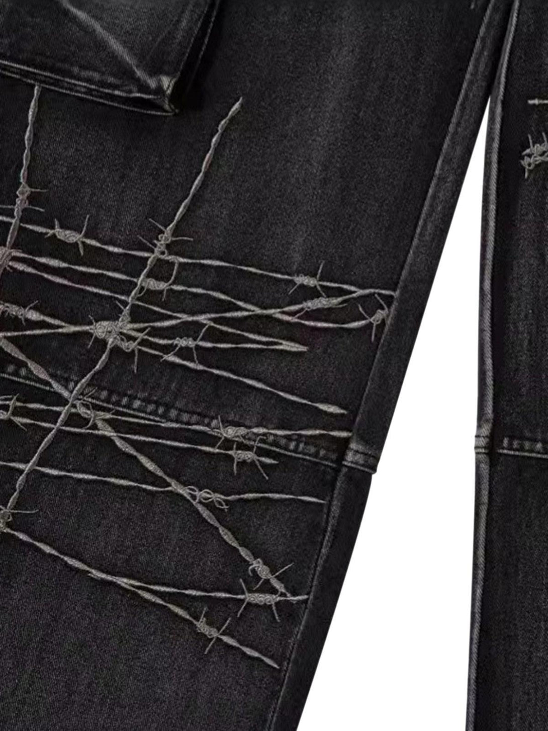 Intricate look at TALISHKO hip-hop jeans featuring barbed wire embroidery on dark fabric.