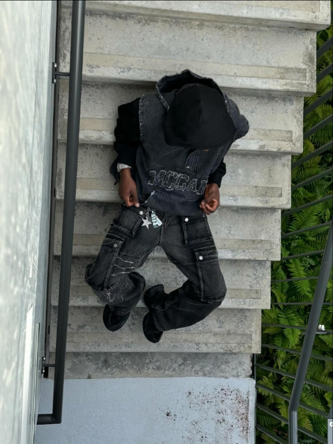 Model on stairs wearing TALISHKO hip-hop jeans with distinctive embroidery and cargo pockets.