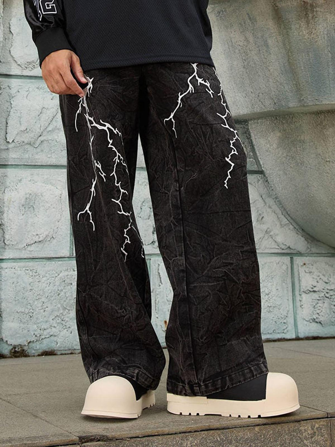 TALISHKO distressed jeans with white lightning details, styled casually for a streetwear vibe.