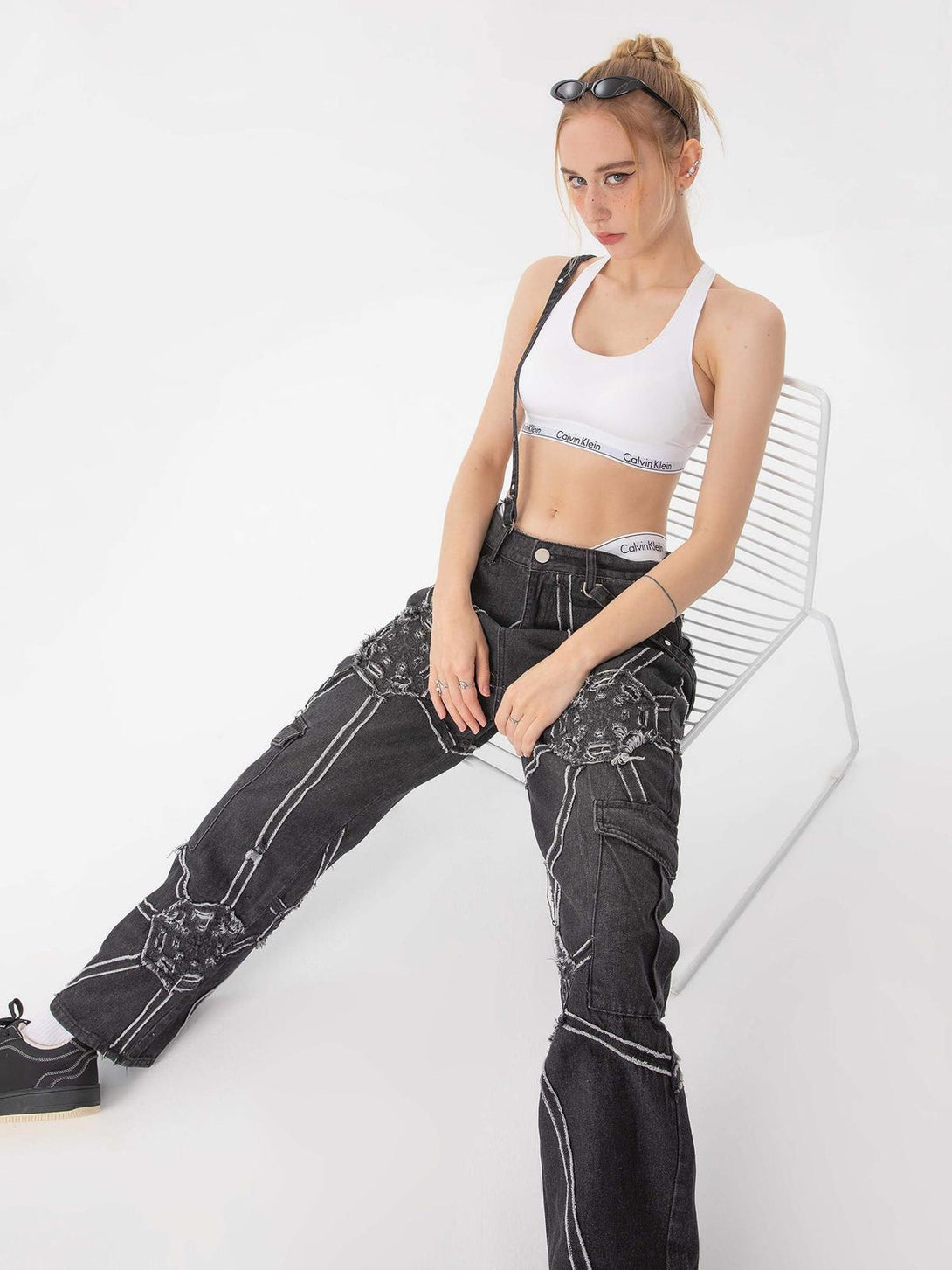 Model in TALISHKO hip-hop spider web denim pants, styled with a sporty crop top ensemble.