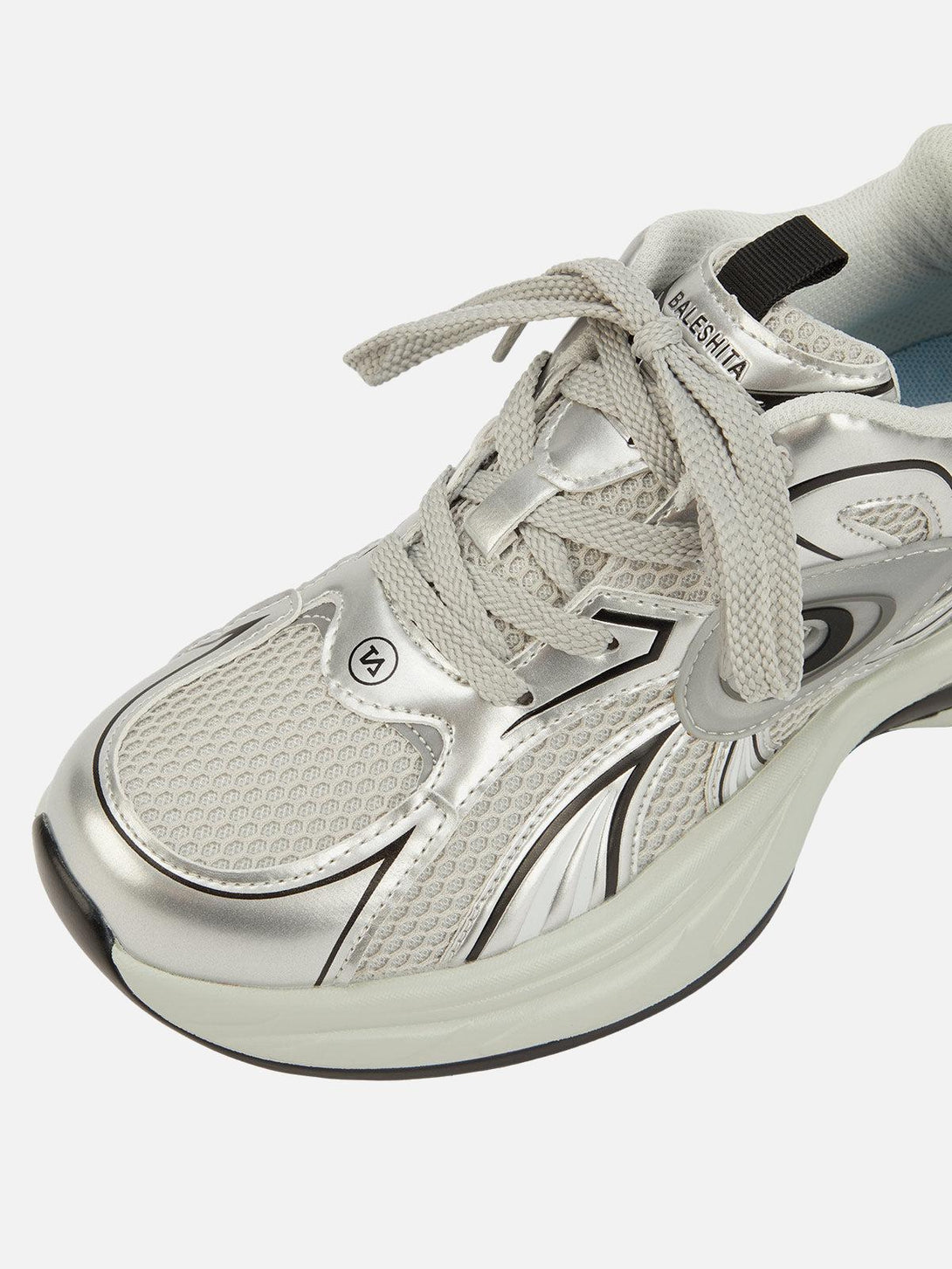 Close-up of TALISHKO sneakers in silver, highlighting mesh texture and sleek design.