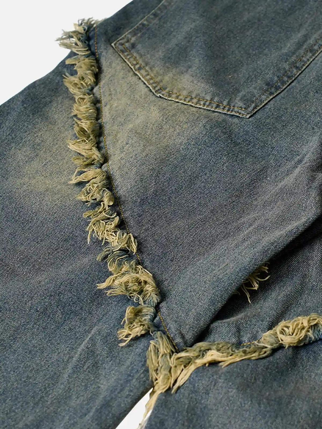 Focusing on the frayed details of TALISHKO's washed distressed jeans, highlighting unique texture.