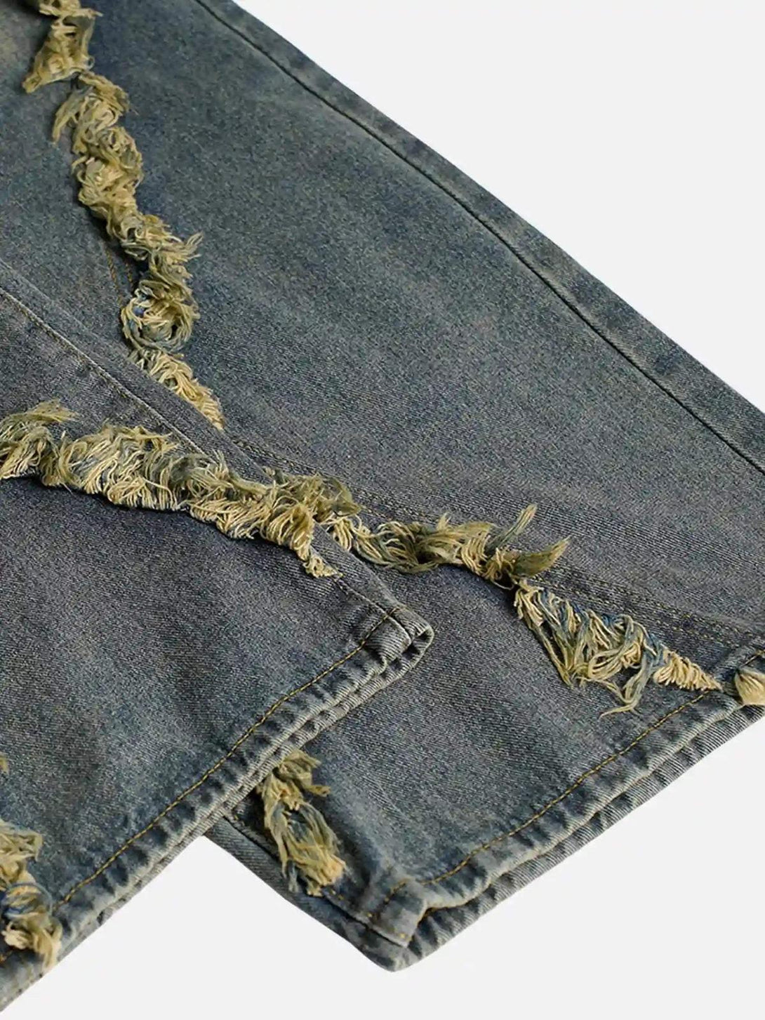 Intricate look at TALISHKO's washed distressed jeans, featuring detailed frayed edges.