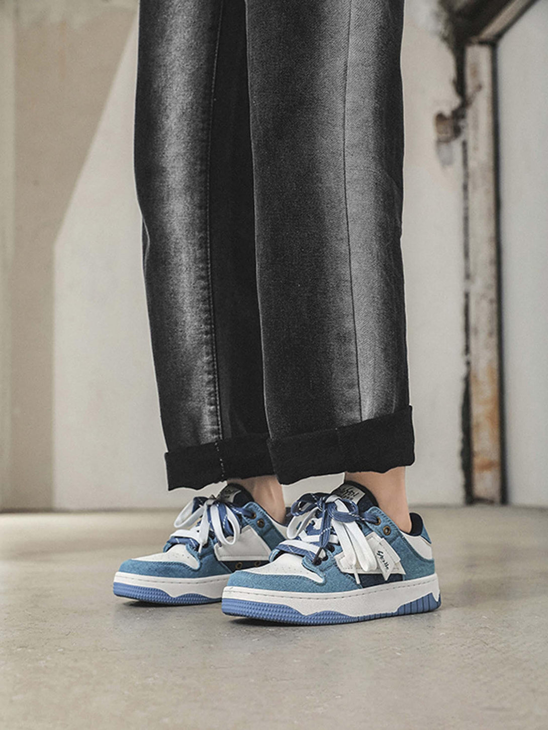 Model wearing TALISHKO sneakers in blue and white, emphasizing casual urban style.