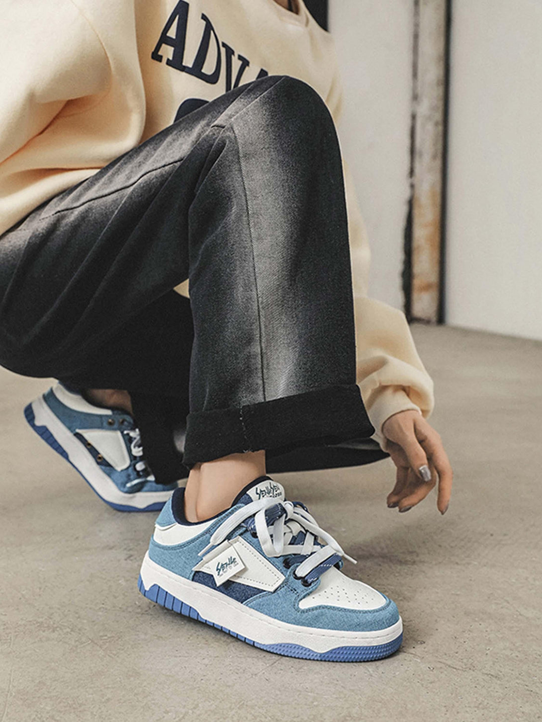 Model wearing blue and white TALISHKO sneakers, highlighting casual urban fashion.