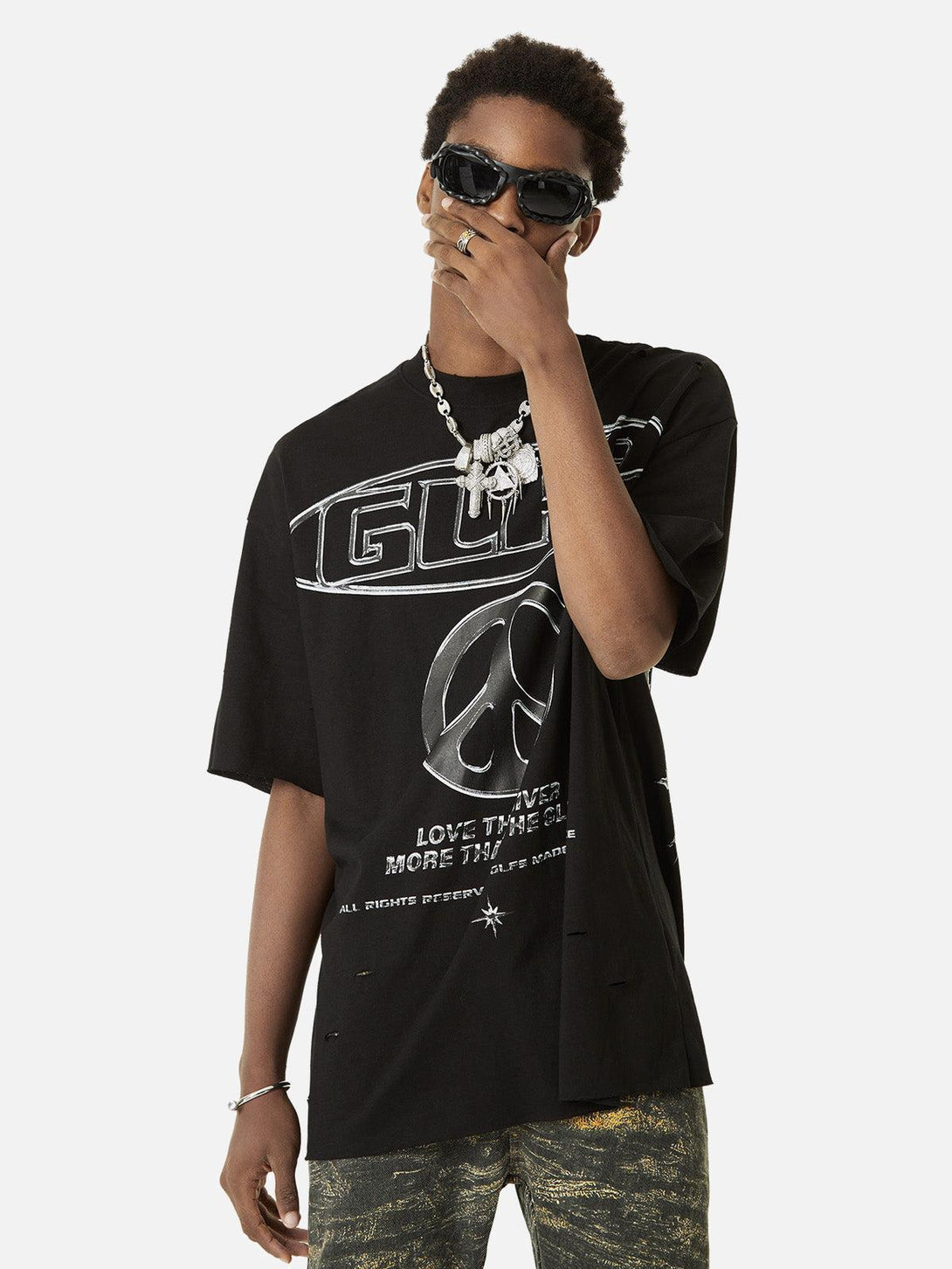 Model styled in black TALISHKO tee with bold graphics, accessorized with sunglasses and jewelry.