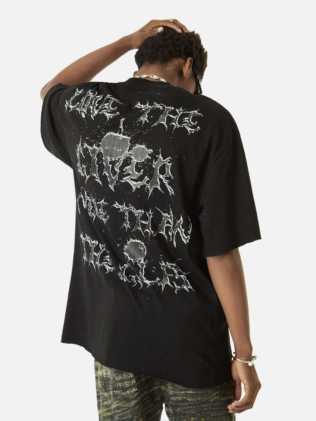 Model in black TALISHKO T-shirt with edgy lettering on back, styled with textured pants.