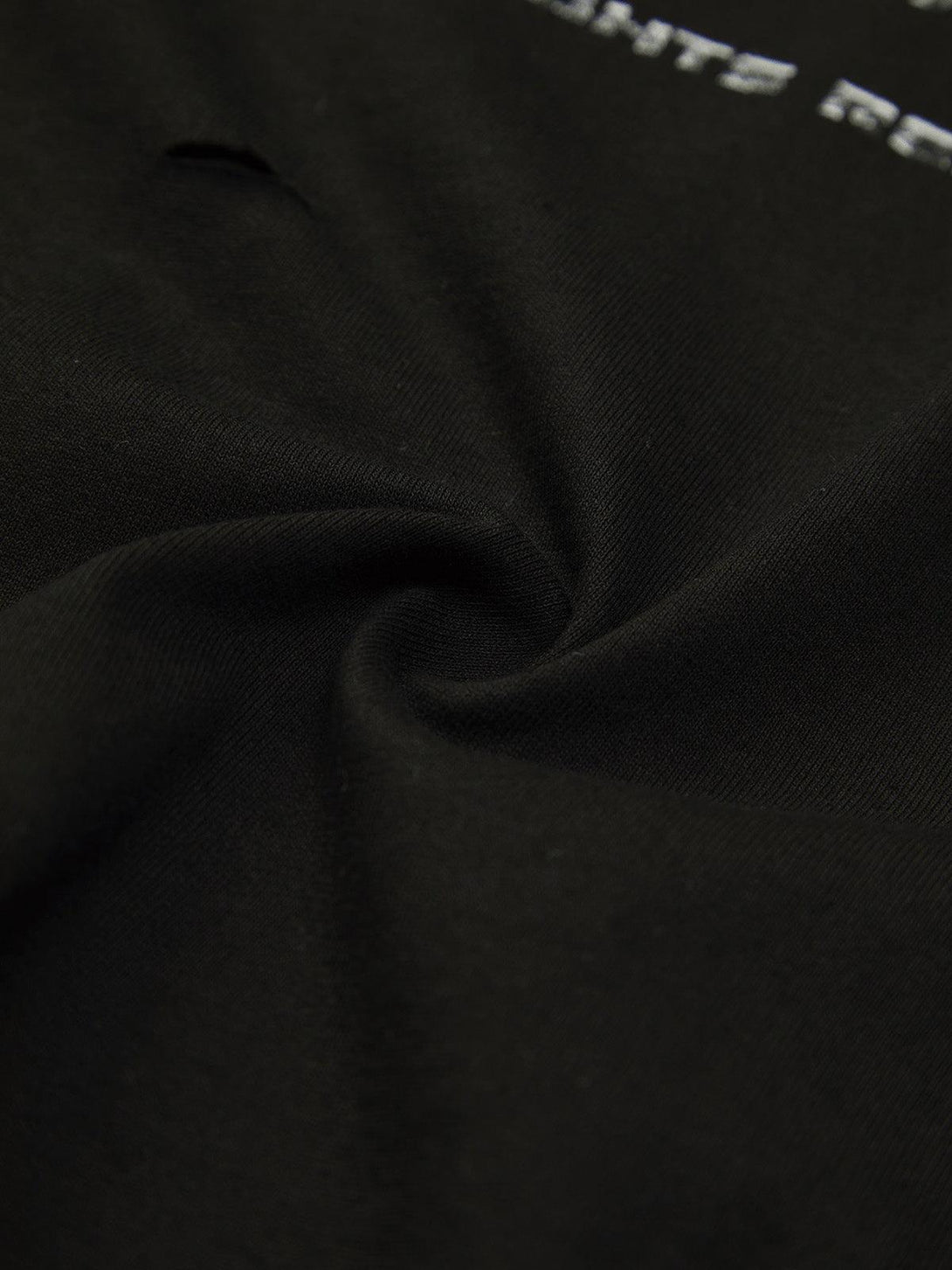 Detailed fabric and stitching of the TALISHKO black T-shirt, highlighting its intricate texture.