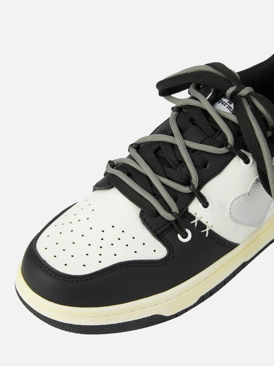 A detailed view of TALISHKO sneakers highlighting black and white design with gray laces.