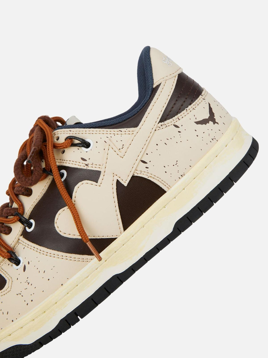 Zoomed-in view of TALISHKO sneakers in cream and brown, highlighting heart and speckled design.
