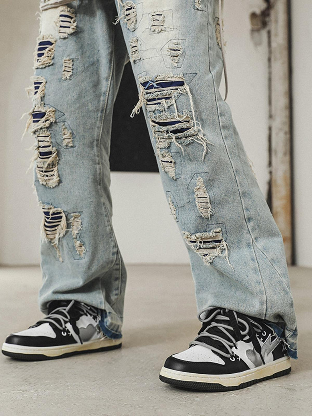 TALISHKO distressed jeans paired with black and white sneakers, highlighting urban street style.