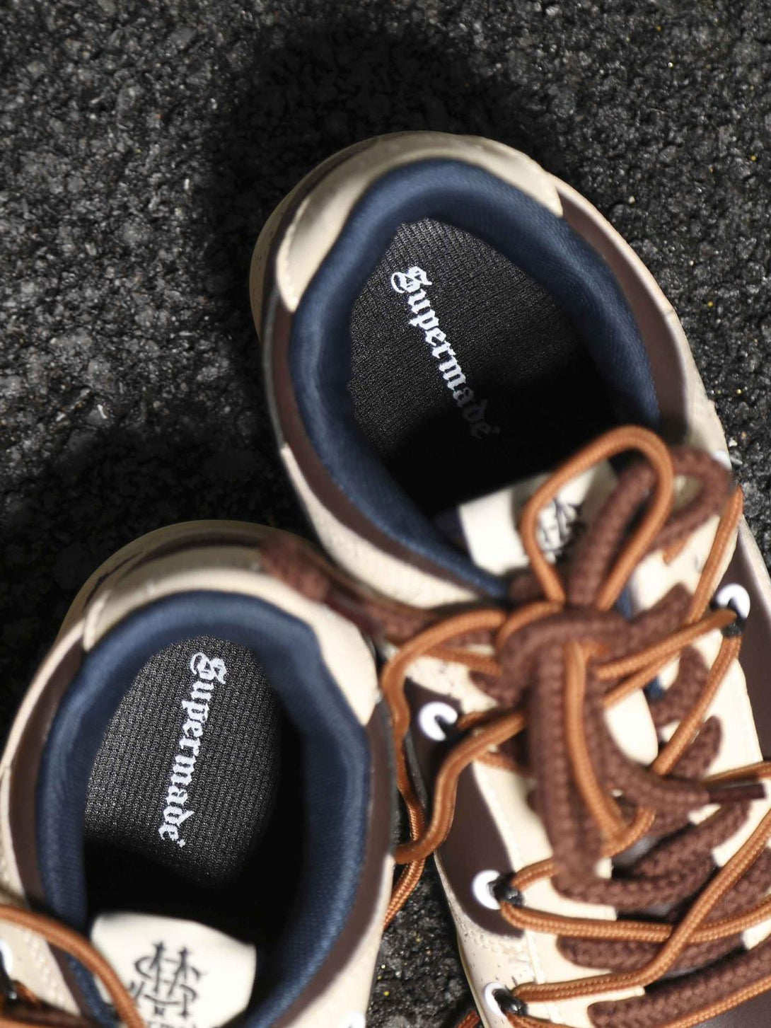 Detailed look at TALISHKO sneakers with contrasting brown laces on a textured surface.