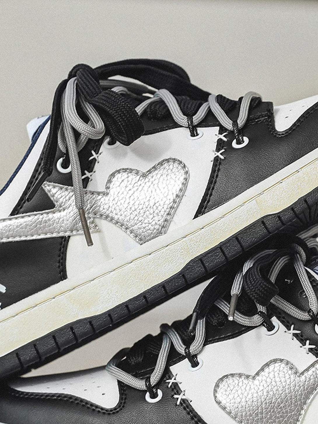 Close-up of TALISHKO sneakers highlighting silver heart design and contrasting black and gray laces.