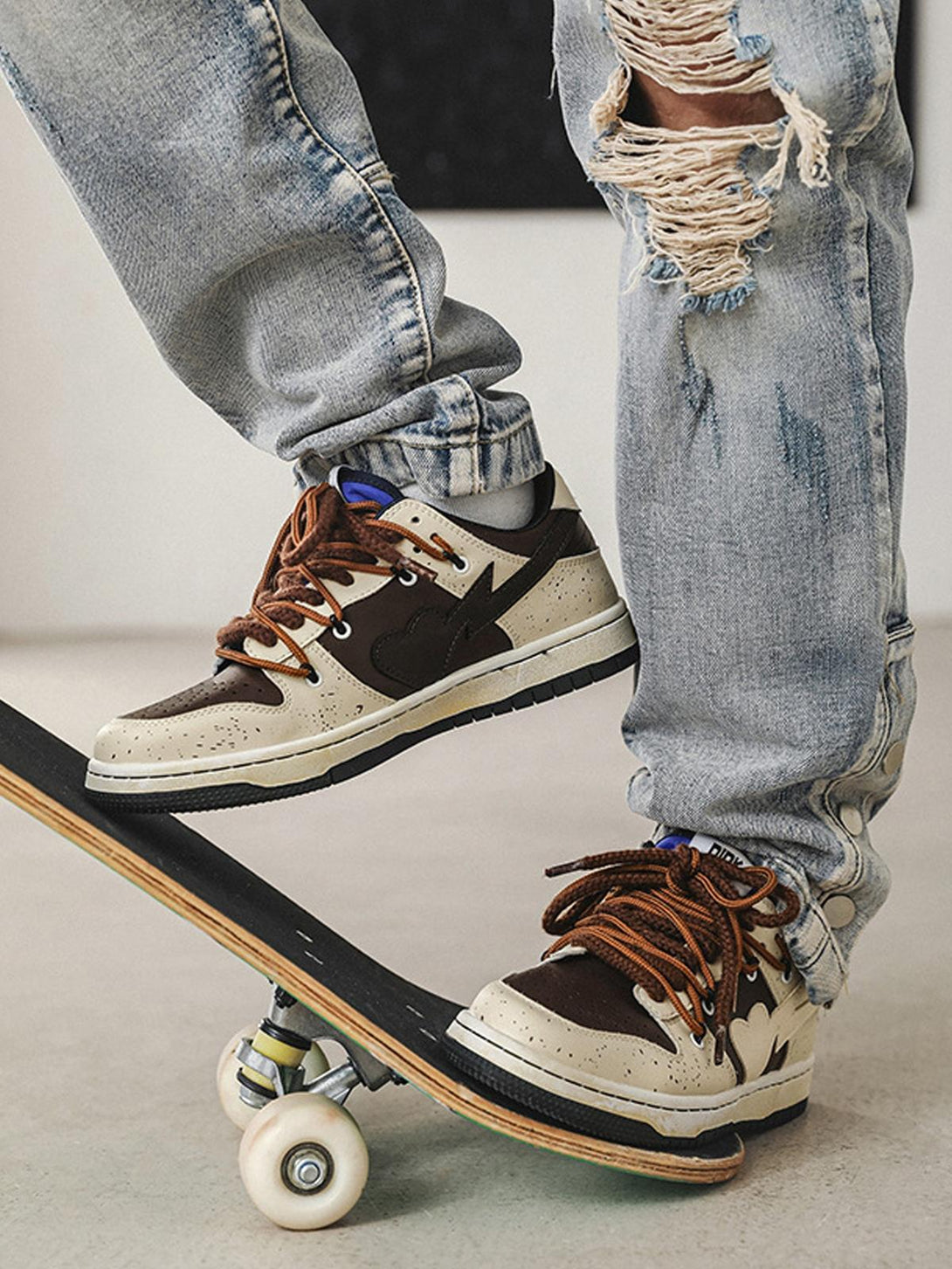 TALISHKO sneakers on a skateboard, paired with distressed jeans for a trendy street style.