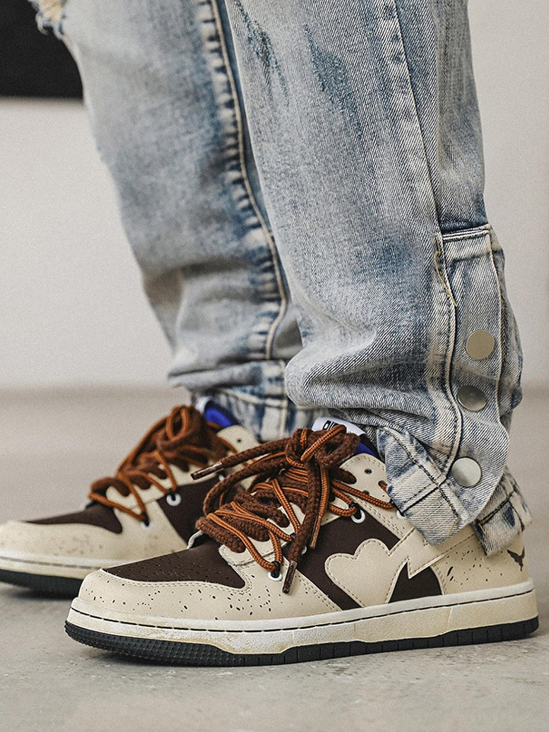 TALISHKO High Street Love Sneakers with brown laces paired with distressed denim for a stylish look.