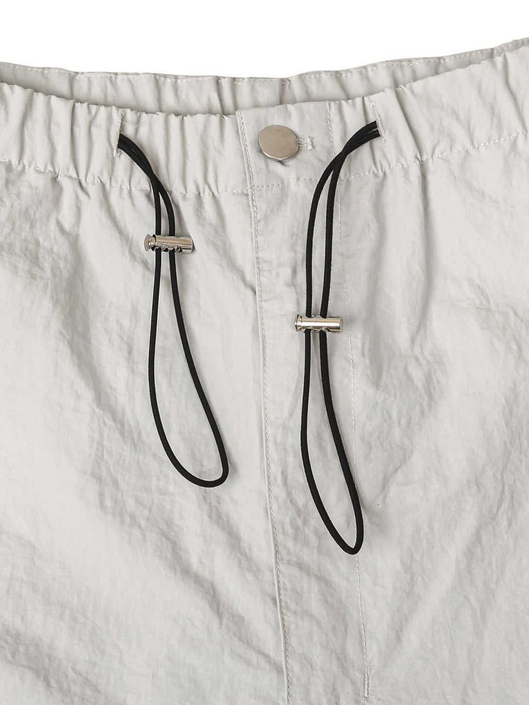 A detailed view of TALISHKO cargo pants' drawstring waist and button closure, highlighting casual style.