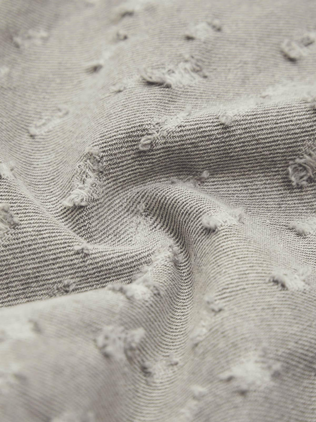 Texture and pattern showcased in TALISHKO's gray ripped denim shorts, highlighting unique design.