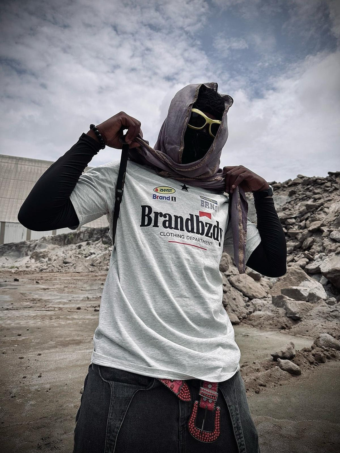 Model wearing TALISHKO white jersey T-shirt with retro badges, styled for an urban look.