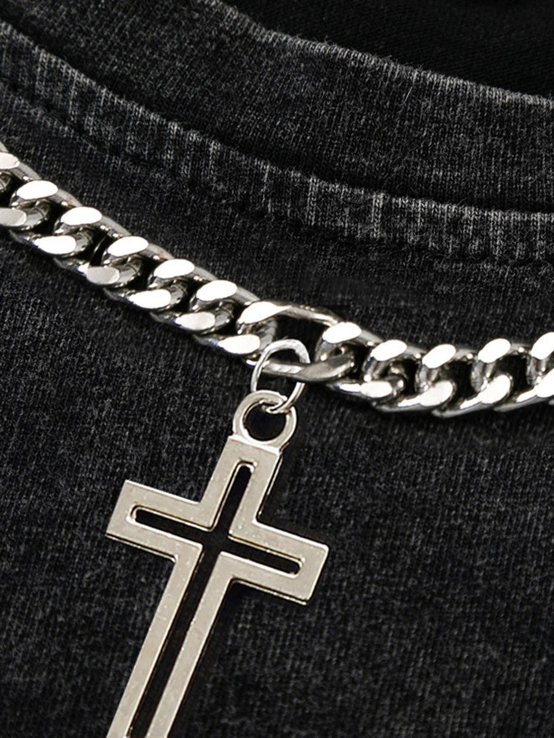 A detailed view of TALISHKO's chain necklace featuring a sleek cross pendant on a dark fabric.
