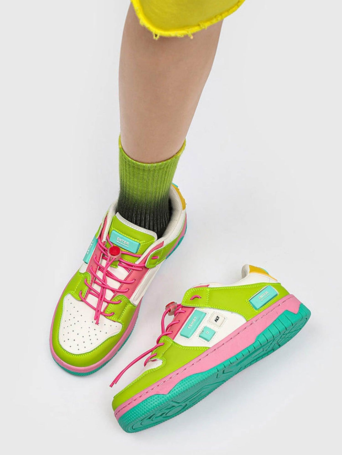 Vibrant green and pink skate shoes by TALISHKO, styled with ombre socks and yellow shorts.